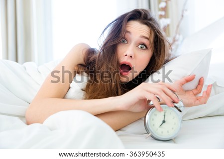 Shocked young woman waking up with alarm  Royalty-Free Stock Photo #363950435
