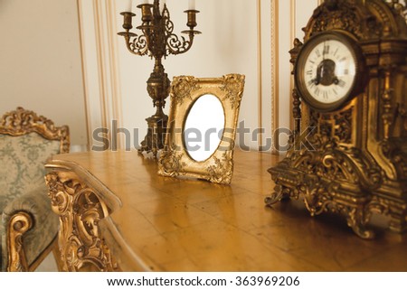 Antique golden frame for photographs on table at luxurious interior