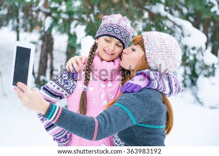 Mom and daughter are photographed in a winter forest, family values. Two girls make a photo on the flatbed in a snowy park