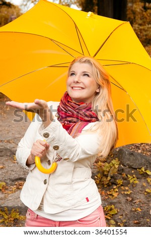 Picture of a beautiful young happy girl in an orange scarf under the yellow autumn  umbrella