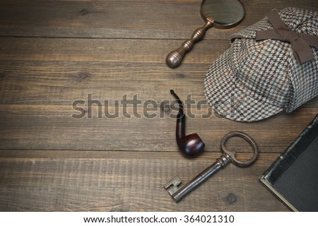 Investigation Concept. Private Detective Tools On The Wood Table Background. Deerstalker Cap, Old Key  And Book, Tobacco  Pipe, Vintage Magnifying Glass. Overhead View
