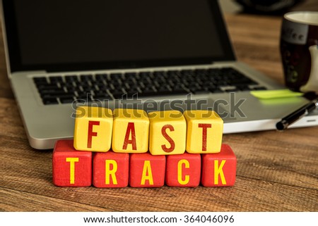 Fast Track written on a wooden cube in a office desk