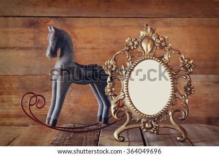 Antique blank victorian style frame and old rocking horse over wooden table