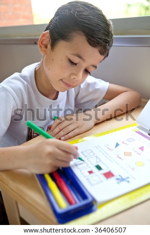 Young boy engross doing his math coloring homework