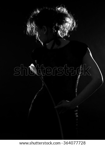 Russian curly slim girl Silhouette in a black dress on a black background with calla lilies