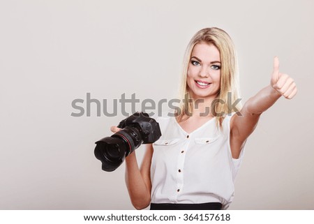 Photographer girl shooting images. Lovely blonde woman with professional camera thumb up hand sign gesture