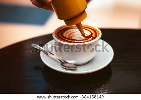Barista creates a picture in a cup of cappuccino
