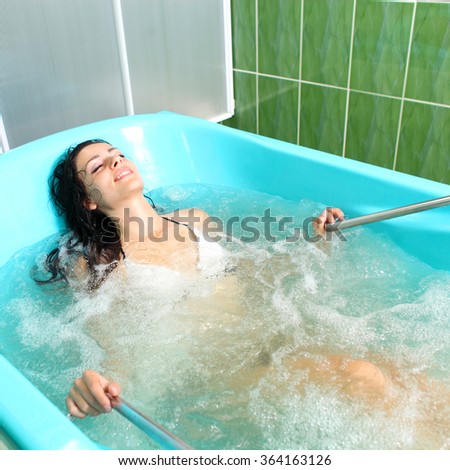 A girl and a hydro massage. She receives medical treatments for relaxation.