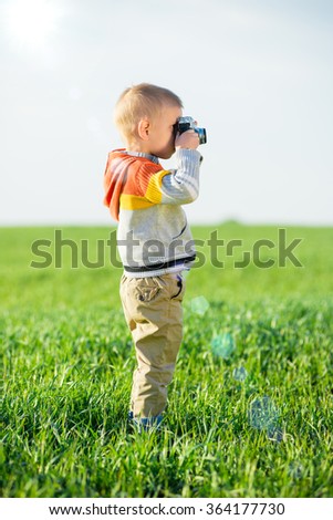 Little boy with an old camera shooting outdoor.