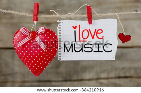I love music Concept. Red hearts and note paper sheet with written message spelling I love music hanging on rope