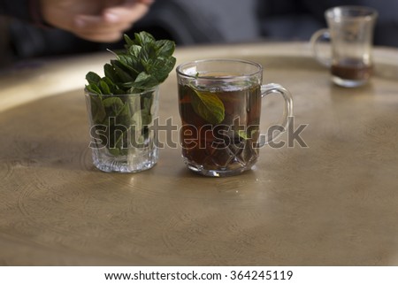 oriental mint tea in a glass/male hand with oriental mint tea in a glass