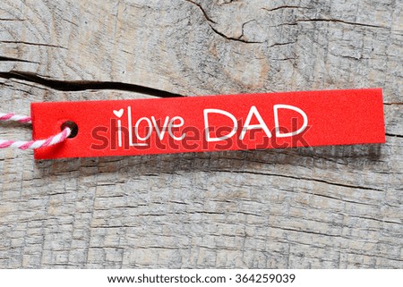 Red label or tag with lettering I love dad on wooden background