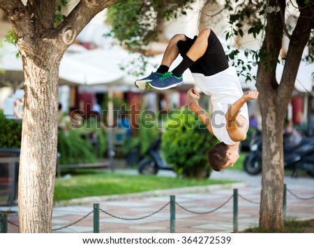 Young sportsman doing front flip in the street Royalty-Free Stock Photo #364272539