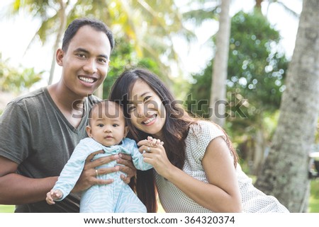 portrait of a beautiful asian young family having fun with his baby on a sunny day