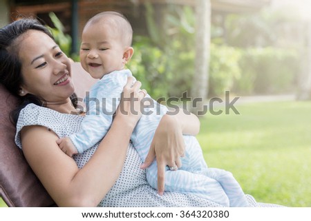 portrait of a beautiful asian mother having fun with his baby on a sunny day