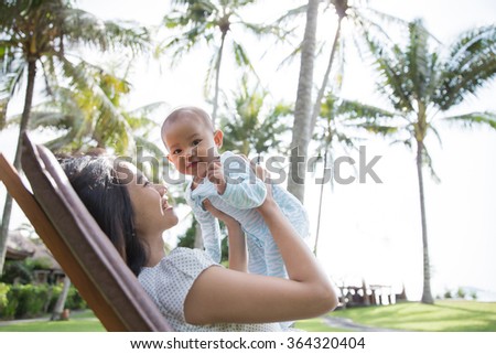 portrait of a beautiful asian mother having fun with his baby on a sunny day