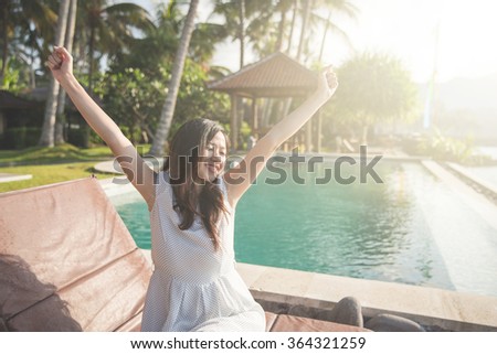 Closeup portrait of pretty girl raise her hands enjoying sunlight on tropical beach, luxury spa resort, travel and tourism concept