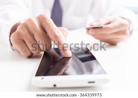 Closeup of man's hands holding credit cards and using mobile phone. Concept for m-commerce, online shopping, m-banking, internet security.