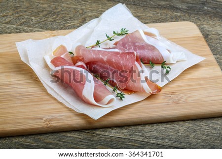 Italian Prosciutto meat with thyme on wood background