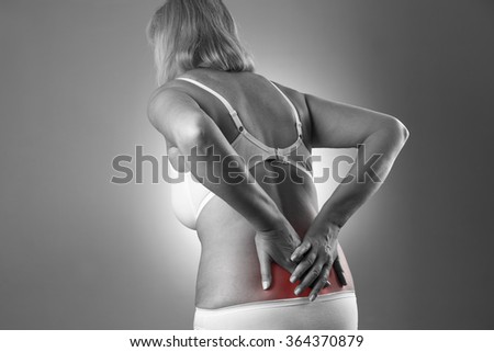 Woman with backache. Pain in the human body on a gray background. Black and white photo with red dot