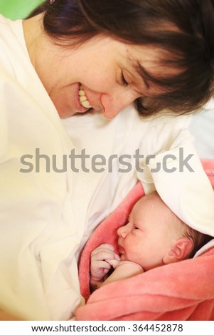 Happy mother with her newborn baby on hospital bed