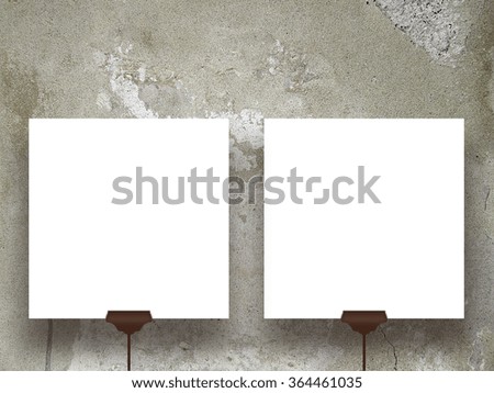 Close-up of two square paper sheets with clips on weathered wall background
