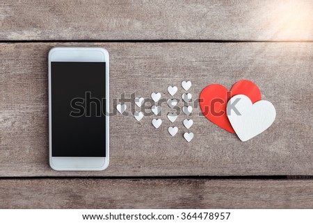 Smartphone and hearts paper on wooden background. valentien or Sending love through social networks