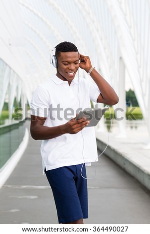Black, African American college student wearing headphones and listening to music on a digital tablet computer