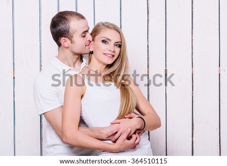Happy couple. Young man and woman have fun near the wooden wall. Both in the white t-shirts.