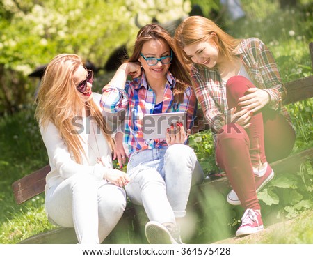 Three friends sitting on a park bench, chatting and enjoying the sunny day