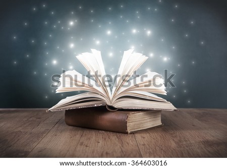 an old open book on a table in front of a blackboard Royalty-Free Stock Photo #364603016