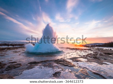 Eruption of Strokkur geyser in Iceland. Winter cold colors, sun lighting through the steam  Royalty-Free Stock Photo #364612373