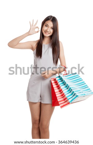 Beautiful young Asian woman show OK sign with shopping bags isolated on white background