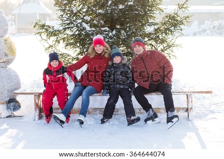 Happy young family skate at the rink in the winter. Beautiful family walking and playing on the ice in winter.