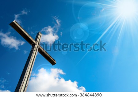 Christian Cross Against a Blue Sky / Wooden christian cross on blue sky with clouds and sun rays