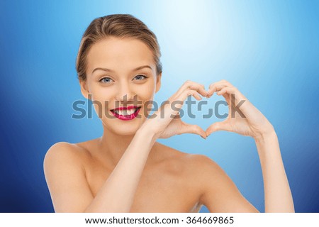 smiling young woman showing heart shape hand sign