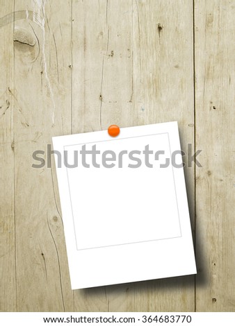 Close-up of one square instant photo frame with pin on light brown wooden boards background