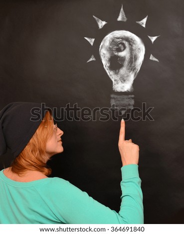 Idea concept. Energy, power, success concept. Education, scientific picture. Young woman with red hair, glasses and cute hipster hat. Girl with finger up and digital drawn light bulb. 