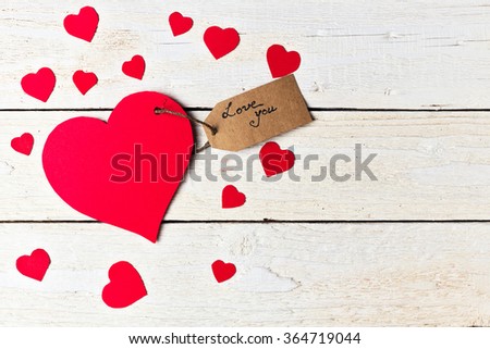 Red heart paper cut with craft label on white wooden background. Valentines day.