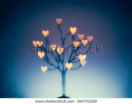 Unfocused background of Valentine tree with bokeh in hearts shape.