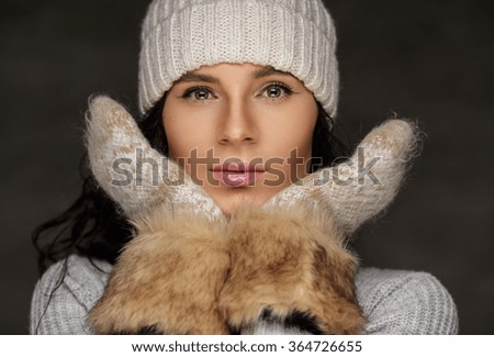 Young woman in white worm winter sweater and in fur gloves.