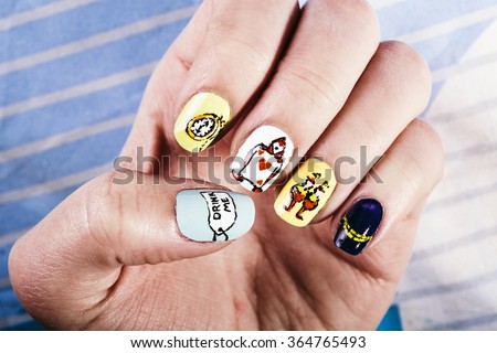 Macro view of a woman's fingernails adorned with Alice in Wonderland themed nail polish art.