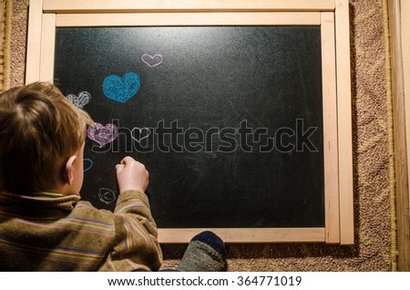 The boy draws heart on the blackboard, valentines day