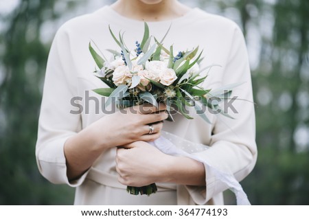 Beautiful bride in a white wedding dress holding her wedding bouquet in the forest