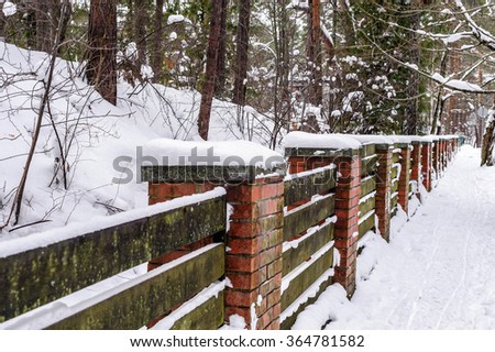 Wooden fence with stone brick columns in winter forest