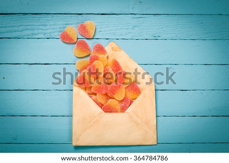 Fruit jelly pink and yellow candy hearts in a envelope, valentines day composition, Blue wooden background
