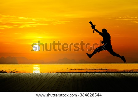 Silhouette of photographer jumping with sunset, seascape. 
