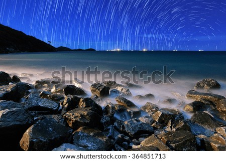 The motion beautiful star trail image during the night in the sea.