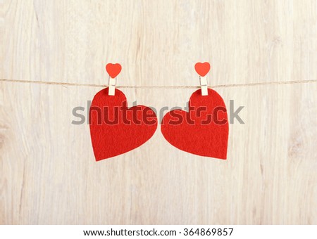 Two red hearts hung on the rope a wooden background