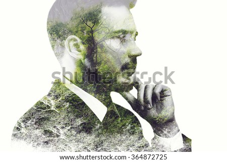 Think green. Digitally composed side view picture of young businessman holding hand on chin and looking away over the picture of green forest